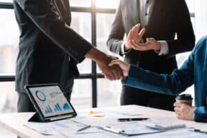 Businessmen shaking hands over a table of search data or any data with graphs during a merger or acquisition